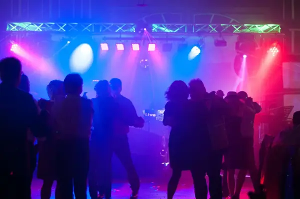 Tanzende Gäste auf Party mit DJ und bunter Clubbeleuchtung in Eventhalle