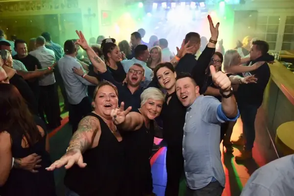 Gruppe feiert auf Tanzfläche im Club, Party mit buntem Licht und Nebel