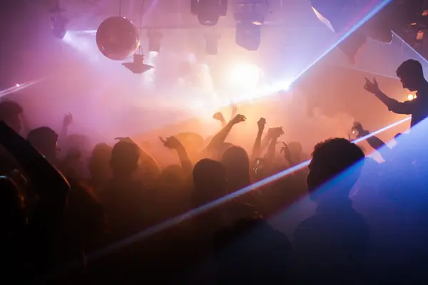 Tanzende Clubmenge mit Laserlicht und Nebel bei einer Party im Nachtclub