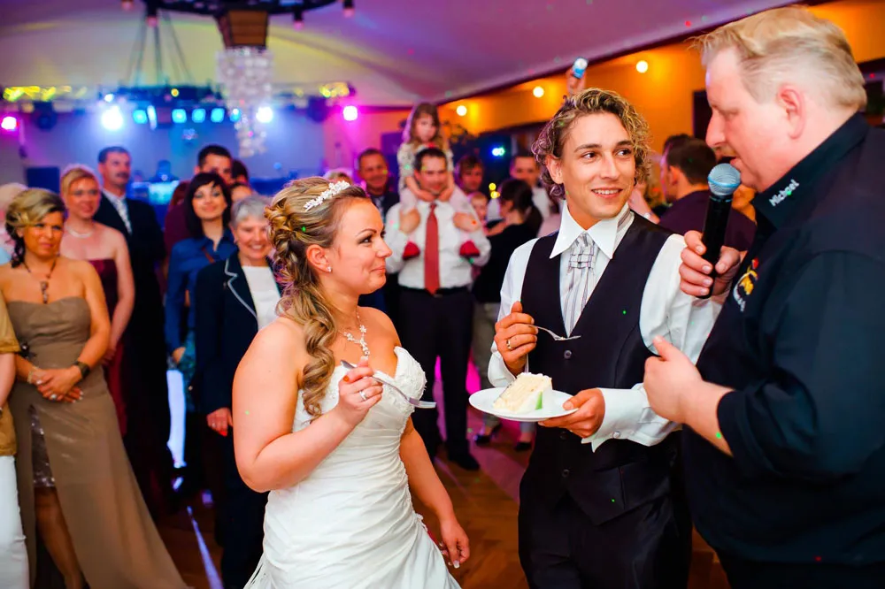 Hochzeitstorte: Braut und Bräutigam mit DJ und Gästen auf der Tanzfläche